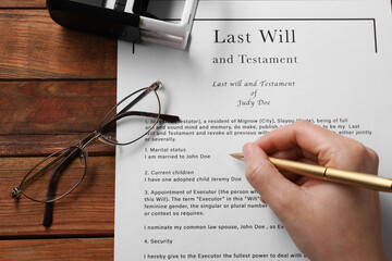Woman signing Last Will and Testament at wooden table, above view