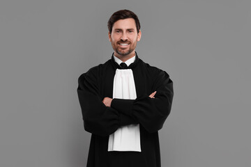 Smiling judge with crossed arms on grey background