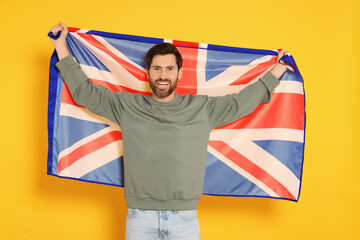 Fototapeta premium Man with flag of United Kingdom on yellow background