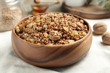 Fresh tasty traditional kutia in wooden bowl on light towel, closeup