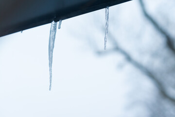 icicle hanging on gutter outside of a house in winter