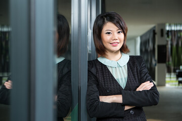 Happy Chinese Business woman standing by window.