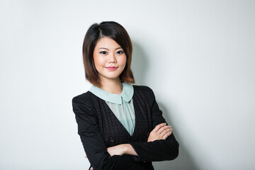 Beautiful Asian business woman leaning wall.