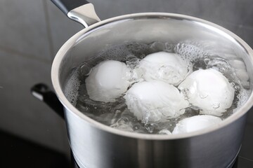 Chicken eggs boiling in saucepan on electric stove, closeup