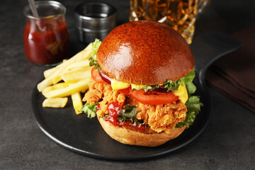 Delicious burger with crispy chicken patty and french fries on black table
