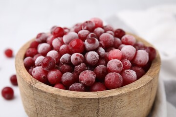 Frozen red cranberries in bowl on table, closeup