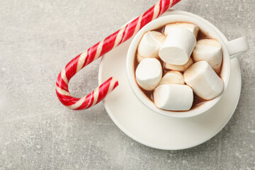 Tasty hot chocolate with marshmallows and candy cane on light grey table, top view. Space for text