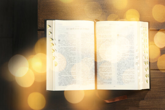 Open Bible on wooden table, top view. Bokeh effect