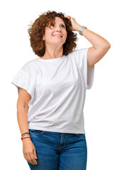 Beautiful middle ager senior woman wearing white t-shirt over isolated background Smiling confident touching hair with hand up gesture, posing attractive