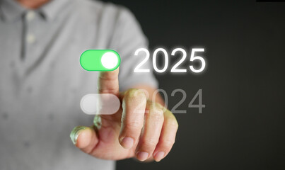 Happy new year 2025. A man tapping on an on-switch of 2025 toggle button to start and welcome the...