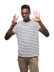 Young african american man wearing glasses and navy t-shirt showing and pointing up with fingers number eight while smiling confident and happy.