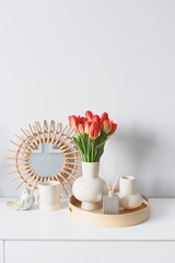 cozy spring home decorations setting with bouquet of red tulips, trendy mirror and candles
