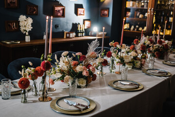 Serving, setting table. Festive dinner table is served dishes and cutlery and decorated with flowers and greenery, candles. Birthday celebration. Family holidays in modern dining restaurant.