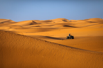 Fototapeta na wymiar ATV machine running on desert dunes in Sahara, Merzouga, Morocco