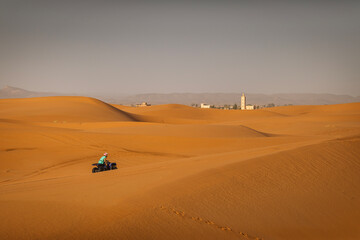 Fototapeta na wymiar ATV machine running on desert dunes in Sahara, Merzouga, Morocco