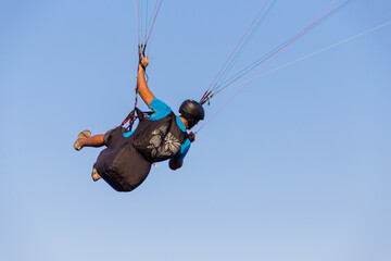 Paraglider flying over the sea coast in blue sky background
