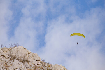 Paraglider flying over the sea coast in blue sky background