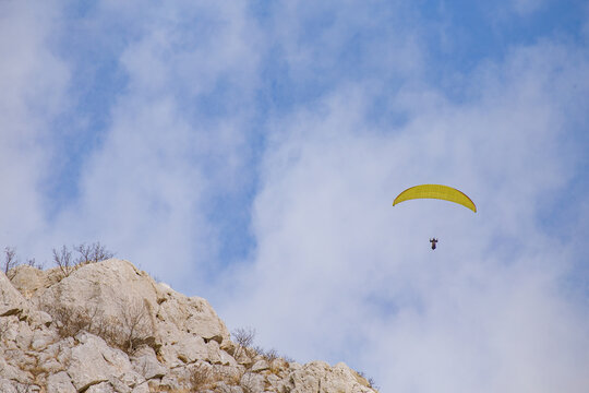 Paraglider flying over the sea coast in blue sky background