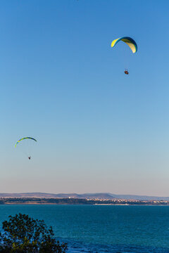 Paraglider flying over the sea coast in blue sky background