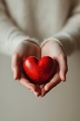 The image features a pair of open hands against a white backdrop, delicately cradling a bright red wood heart