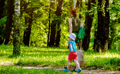 Fototapeta premium A woman and her son are walking in a city park 