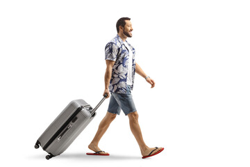 Man in flip-flops pulling a suitcase smiling and walking