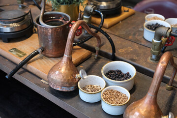 Small copper stills and distilling equipment arranged on a decorated table.