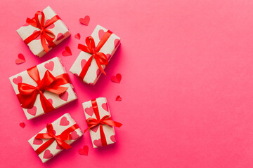 Top view photo of valentine day decorations gift box with red ribbon bow on colored background. Holiday gift boxes with top view