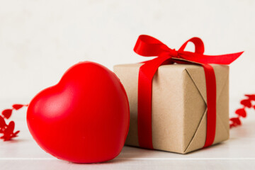 gift box with red bow and red heart on colored background. Perspective view. Flat lay