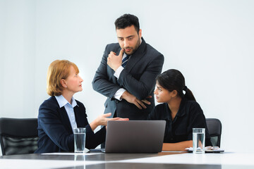 Obraz premium Group of three professional discussing numbers in a business meeting with use laptop. Team of business people brainstorming solutions for a project as they work towards the success of their company.