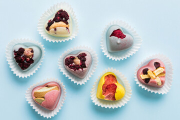 chocolate sweets in the form of a heart with fruits and nuts on a colored background. top view with space for text, holiday concept