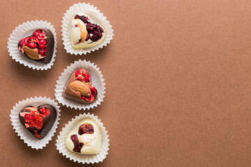 chocolate sweets in the form of a heart with fruits and nuts on a colored background. top view with space for text, holiday concept