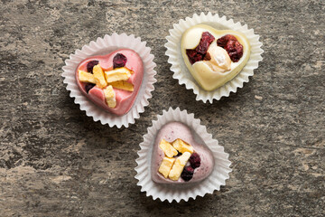 chocolate sweets in the form of a heart with fruits and nuts on a colored background. top view with space for text, holiday concept