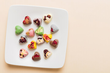 Plate with different chocolate on colored background. Assortment of fine chocolates top view vith copy space Health and obesity concept