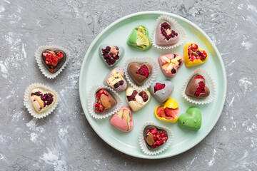 Plate with different chocolate on colored background. Assortment of fine chocolates top view vith copy space Health and obesity concept