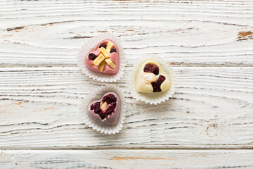 chocolate sweets in the form of a heart with fruits and nuts on a colored background. top view with space for text, holiday concept