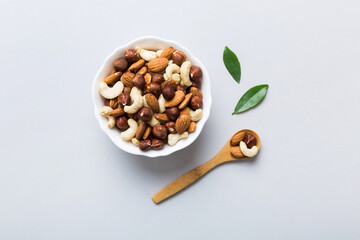 Assortment of nuts in wooden bowl on colored table. Cashew, hazelnuts, walnuts, almonds. Mix of nuts Top view with copy space