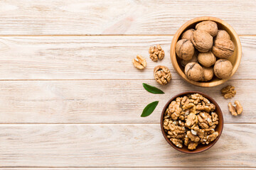 Walnut kernel halves, in a wooden bowl. Close-up, from above on colored background. Healthy eating...