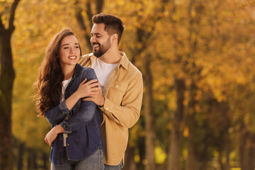 Fototapeta premium Beautiful couple spending time together in autumn park, space for text