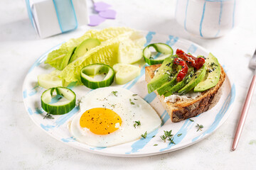 Romantic breakfast for Valentine's Day. Fried egg and toast with avocado and cream cheese.