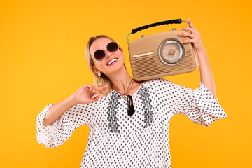 Portrait of happy hippie woman with retro radio receiver on yellow background