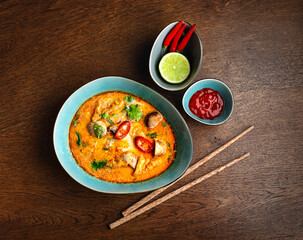 Asian cuisine. Red soup with mushrooms in a blue plate. View from above