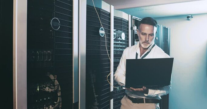 Mature man in server room with laptop, network maintenance and engineer in digital storage for database update. Tech employee, system administration and technician online in data center with computer