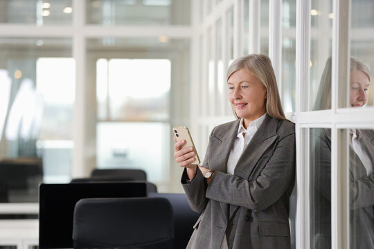 Smiling woman with smartphone in office, space for text. Lawyer, businesswoman, accountant or manager