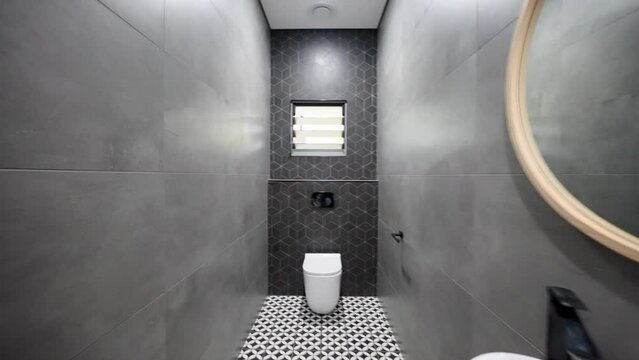 Large modern stand alone toilet. Textured pattern tiles, stylish dark col grey colour with wood vanity contrast