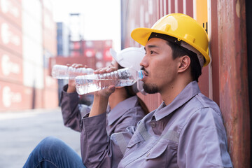 Male container worker drinking water in break time at commercial dock site