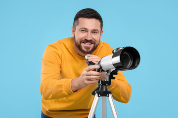 Happy astronomer with telescope on light blue background