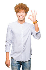 Young handsome business man with afro hair wearing elegant shirt smiling positive doing ok sign with hand and fingers. Successful expression.