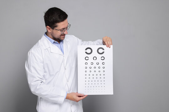 Ophthalmologist with vision test chart on gray background, space for text