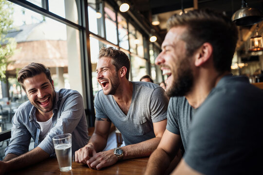 A group of male friends hanging out in a bar, or a restaurant, talking and laughing, enjoying their time together.
